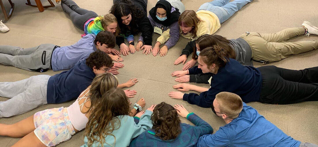 Students laying on the floor forming a circle 